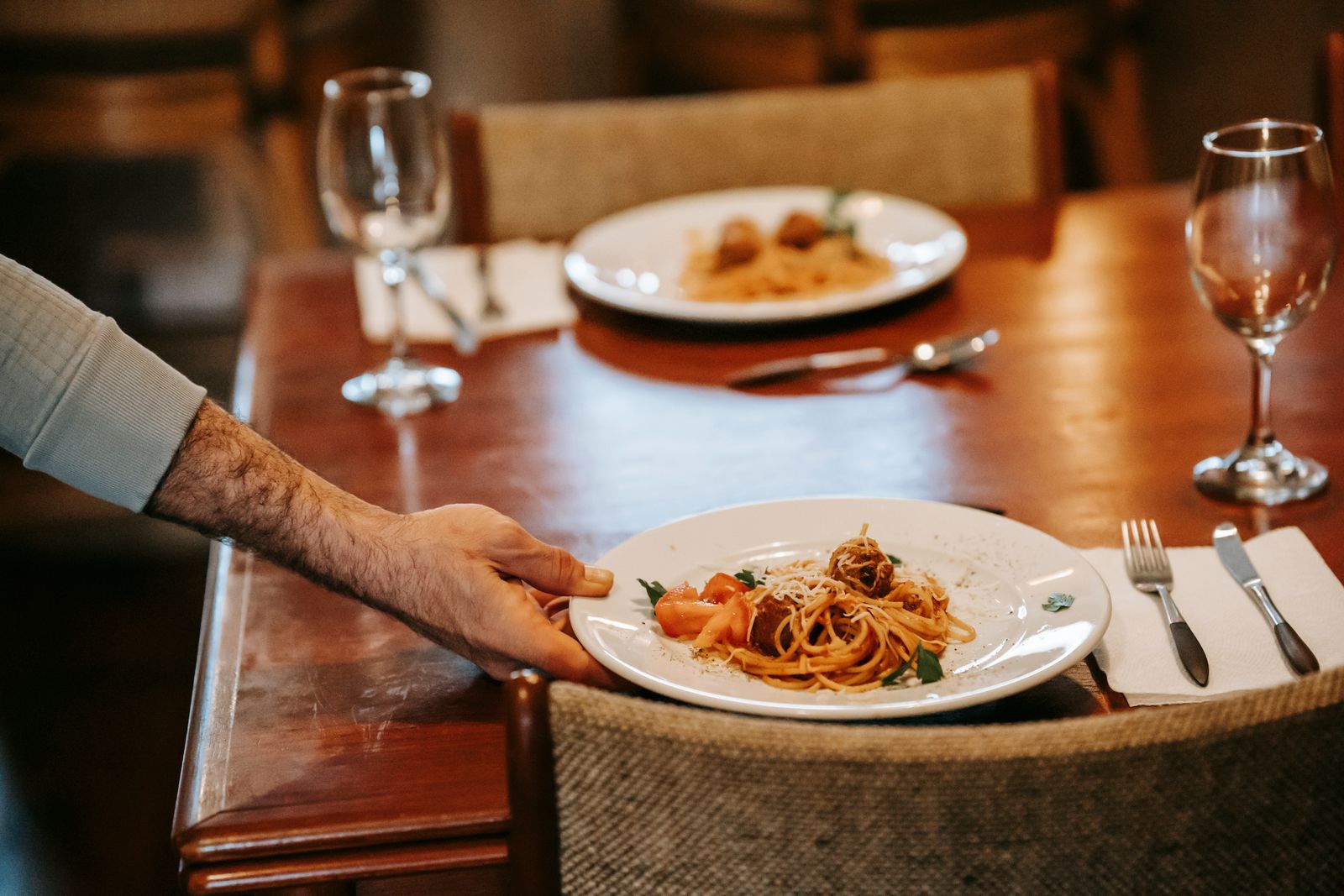 Waiter serving a plated meal at a restaurant table